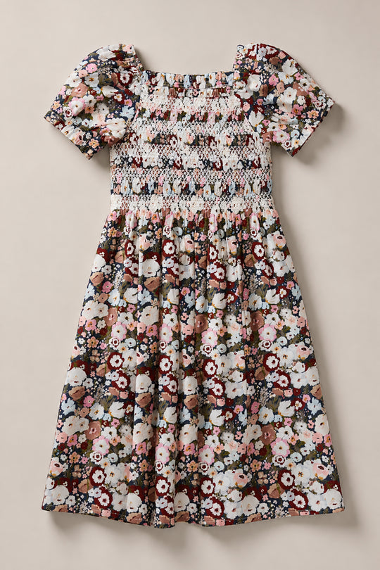 Introducing the Mini Sunday Best Dress in Midnight Garden by Ivy City Co—a charming mini dress showcasing a colorful floral pattern on a light background. Designed with short puff sleeves, a smocked bodice, and a square neckline, it features a gathered skirt for an effortlessly sweet look.