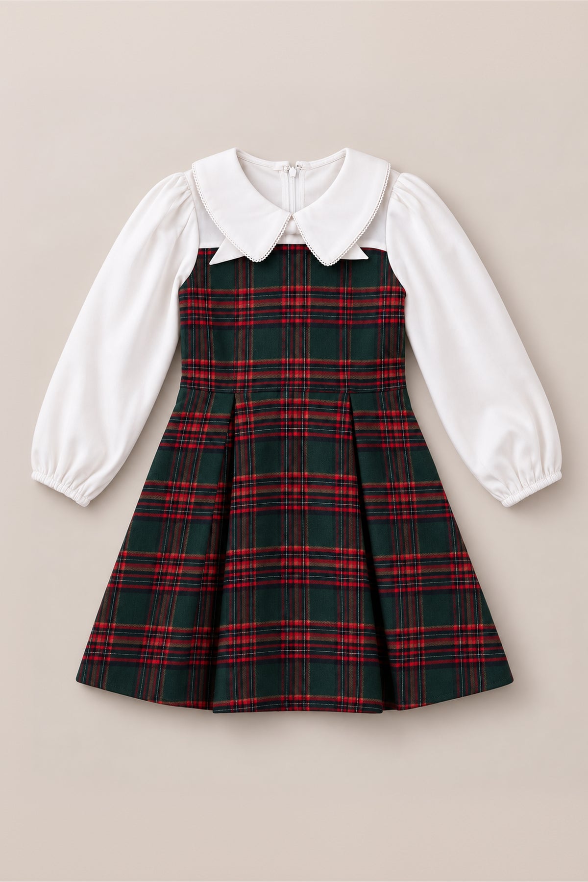 The Mini Tawny Dress in Evergreen Plaid by Ivy City Co features a red and green plaid skirt and bodice, crisp white long puffed sleeves, and a timeless white Peter Pan collar. Displayed on a neutral background, this charming dress is perfect for Christmas celebrations or any holiday portrait occasion.