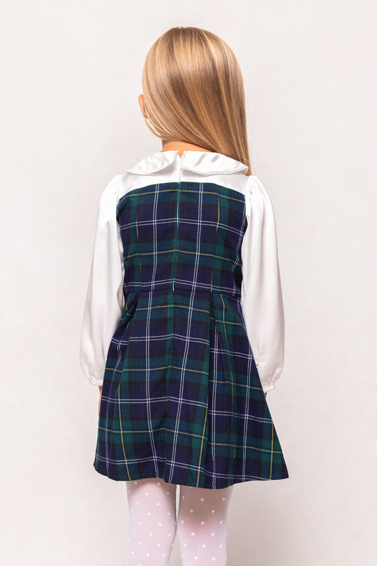 Person wearing a plaid dress over a white shirt on a plain background