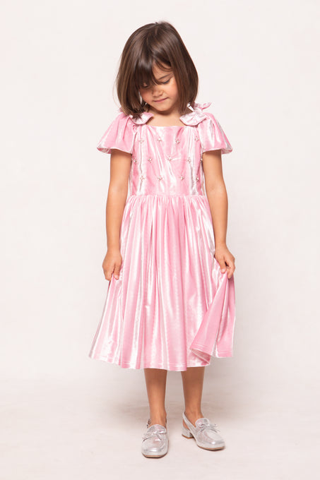 Young girl wearing a pink dress with ruffled sleeves on a white background