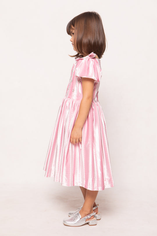Young girl wearing a pink dress with a white background