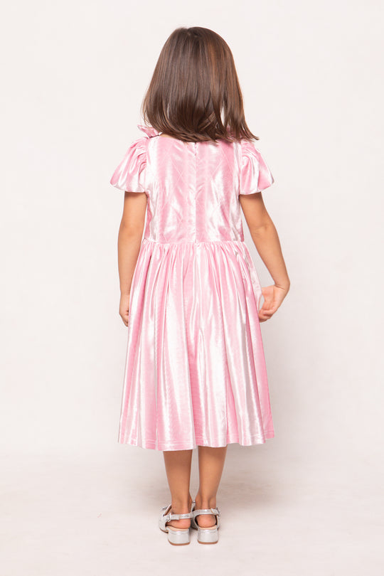 Young girl wearing a pink dress against a white background
