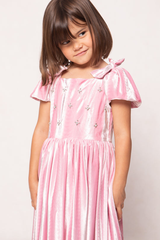 Young girl wearing a pink dress with a white background