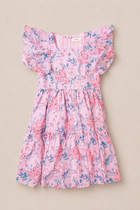The Mini Trixie Dress in Pink Sketched Flower Chiffon by Ivy City Co features blue and red floral patterns, short ruffled sleeves, a fitted bodice, and a tiered skirt—beautifully displayed flat on a beige background.