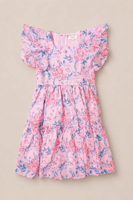 The Mini Trixie Dress in Pink Sketched Flower Chiffon by Ivy City Co features blue and red floral patterns, short ruffled sleeves, a fitted bodice, and a tiered skirt—beautifully displayed flat on a beige background.