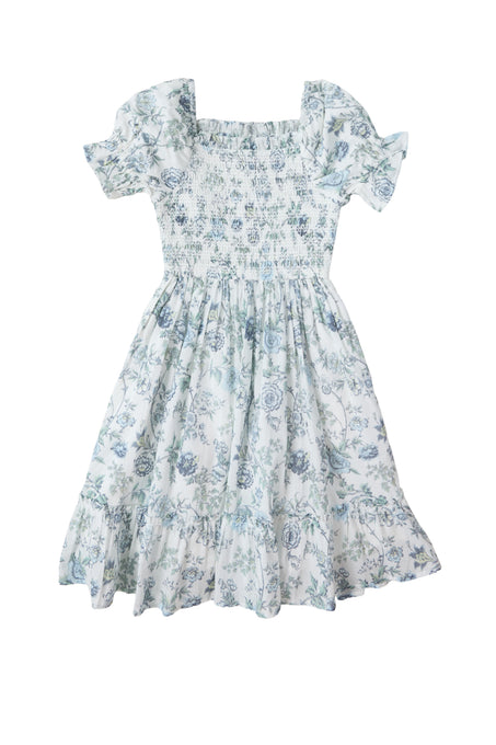 The Ivy City Co Mini Valencia Dress in Ivory Climbing Vine Bloom is a girls’ smocked dress with short puff sleeves, a smocked bodice, flared skirt, and a light blue and white vintage-inspired floral pattern.