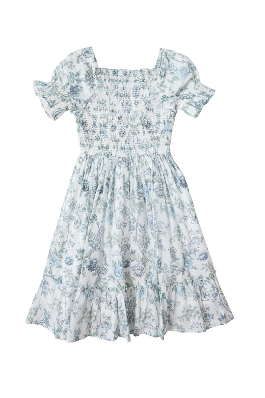 The Mini Valencia Dress in Ivory Climbing Vine Bloom by Ivy City Co is a light blue and white cotton midi dress featuring short puff sleeves, a smocked bodice, square neckline, ruffled hem, and a vintage-inspired floral pattern.