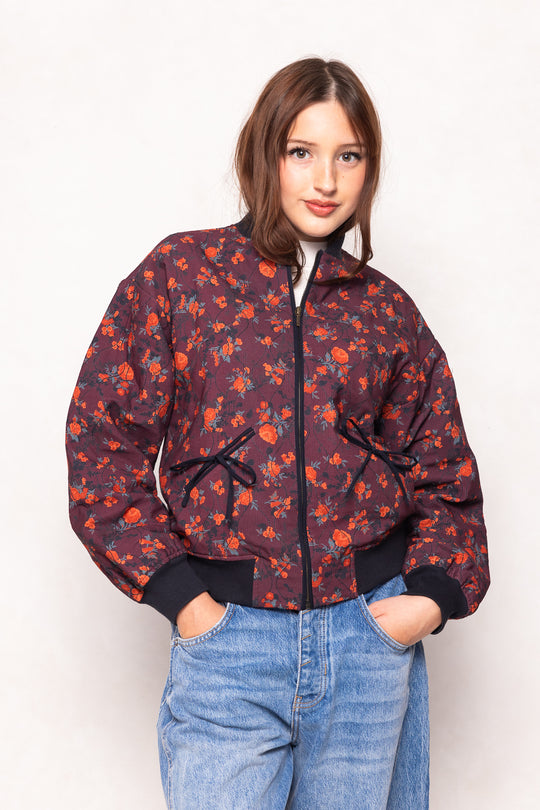 Woman wearing a floral patterned jacket and blue jeans on a white background