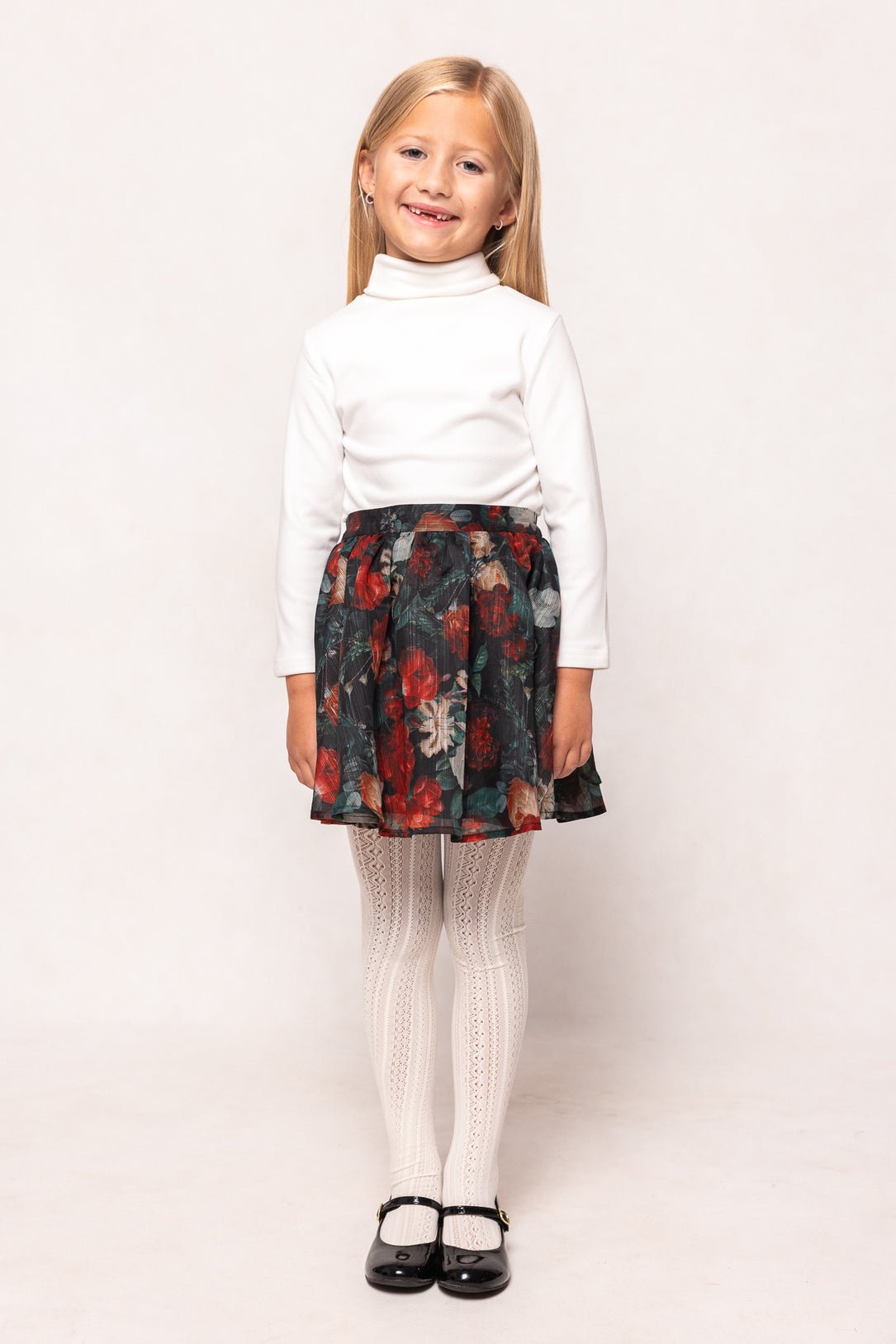 Young girl wearing a white blouse and floral skirt on a white background
