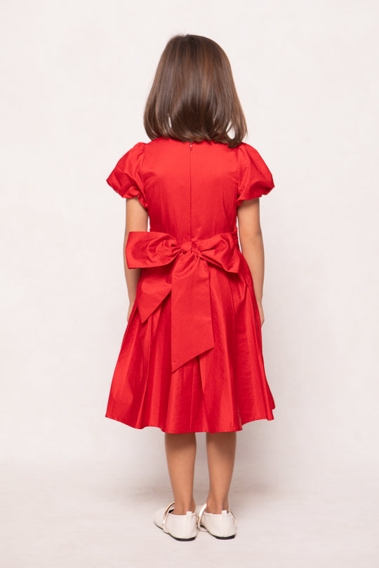 Red dress with a large bow on the back worn by a person on a white background