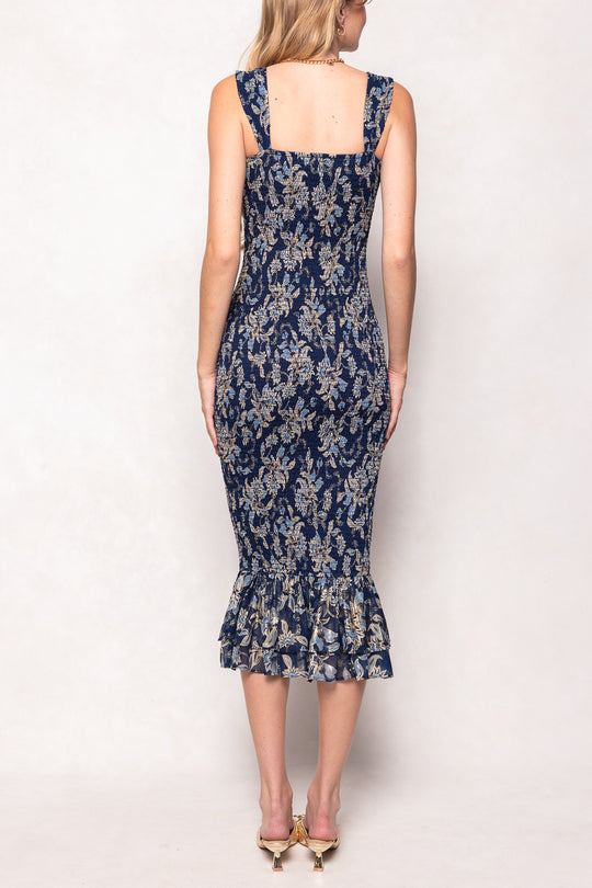 Woman wearing a navy floral dress with a plain white background