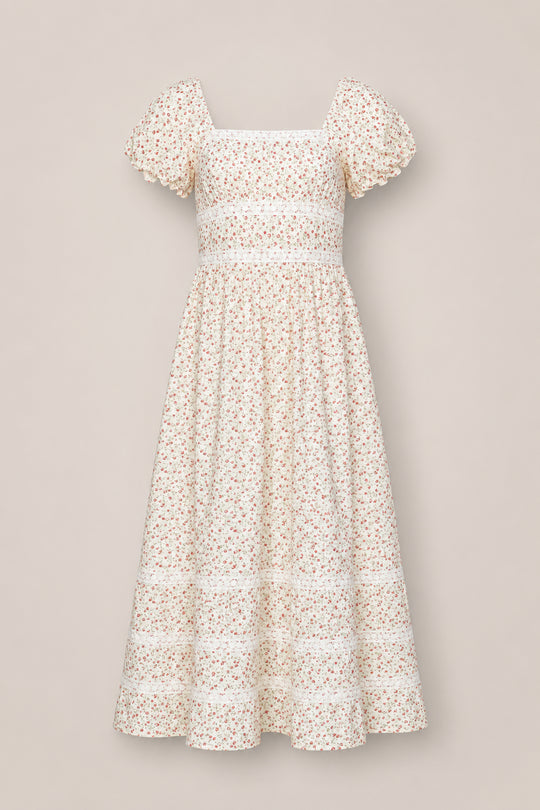 The Mirabelle Dress in Cream Ditsy Floral by Ivy City Co is a cream-colored cotton dress adorned with a small pink floral print. It features short sleeves with scalloped edges, a square neckline, a fitted smocked bodice, and a flared tiered skirt.