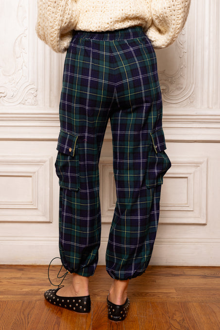 Plaid pants worn by a person against a decorative wall.