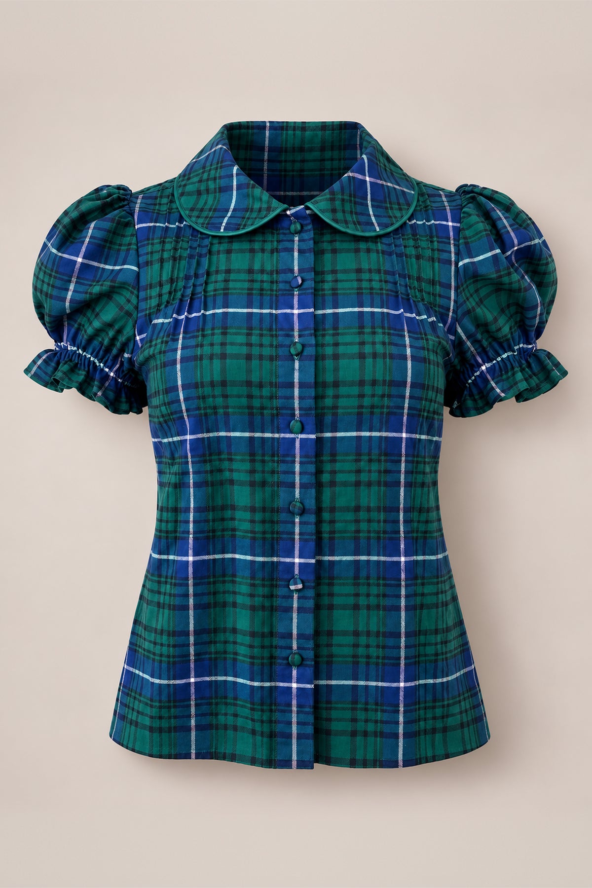 The Nicolette Blouse in Emerald Plaid by Ivy City Co features green and blue checks, a Peter Pan collar, puffed short sleeves with ruffled cuffs, pleated detailing on the chest, and front buttons—making it a perfect girls’ holiday blouse. Shown against a plain beige background.