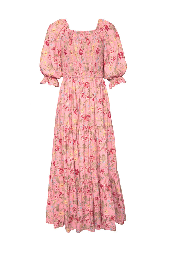 The Madeline Maxi Dress in Pink Vintage Poppies by Ivy City Co is a long, pink floral maxi dress with puffed short sleeves, a smocked bodice, and a tiered skirt. Featuring red and yellow poppy patterns and ruffled sleeve hems, this elegant dress is also nursing-friendly—making it perfect for any occasion.