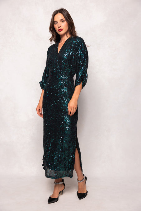 Woman wearing a dark green sequin dress on a white background