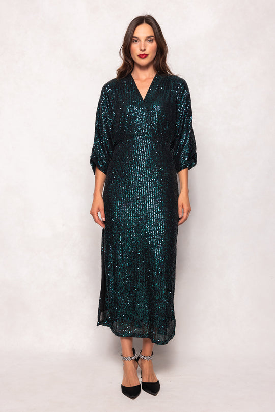 Woman wearing a dark green sequin dress against a white background
