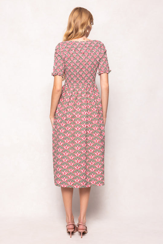 Woman wearing a pink and green patterned dress on a white background