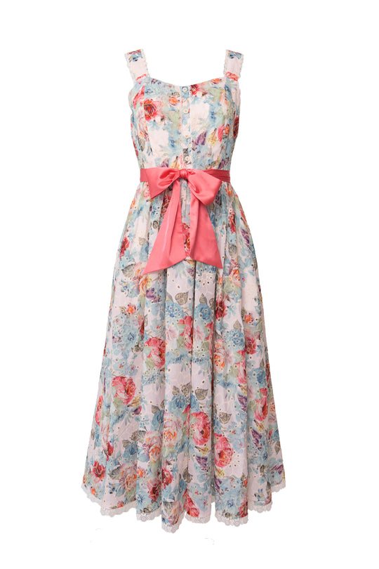 The Ivy City Co Penny Tank Midi Dress in Multicolor Floral is a sleeveless, cotton midi dress with blue, pink, and white florals, a fitted bodice, button front, and a large pink waist bow—perfect for any occasion.