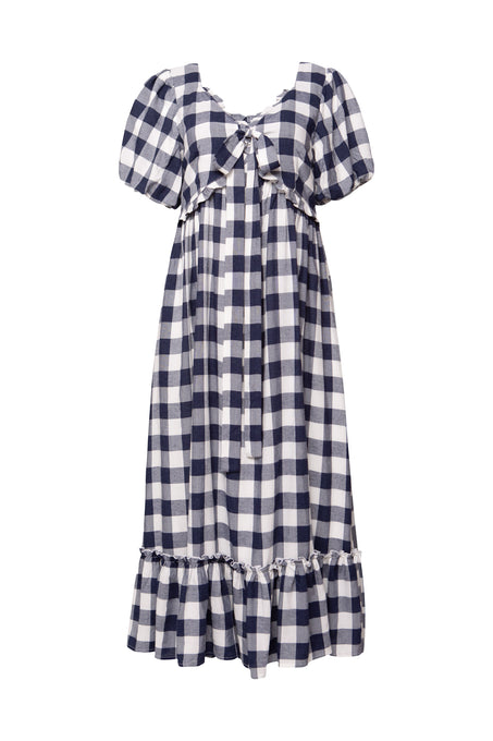 The Picnic Dress in Navy Gingham by Ivy City Co features puff short sleeves, a bow at the chest, empire waist, and ruffled knee-length hem—making it an ideal picnic dress thats also beautifully maternity friendly.