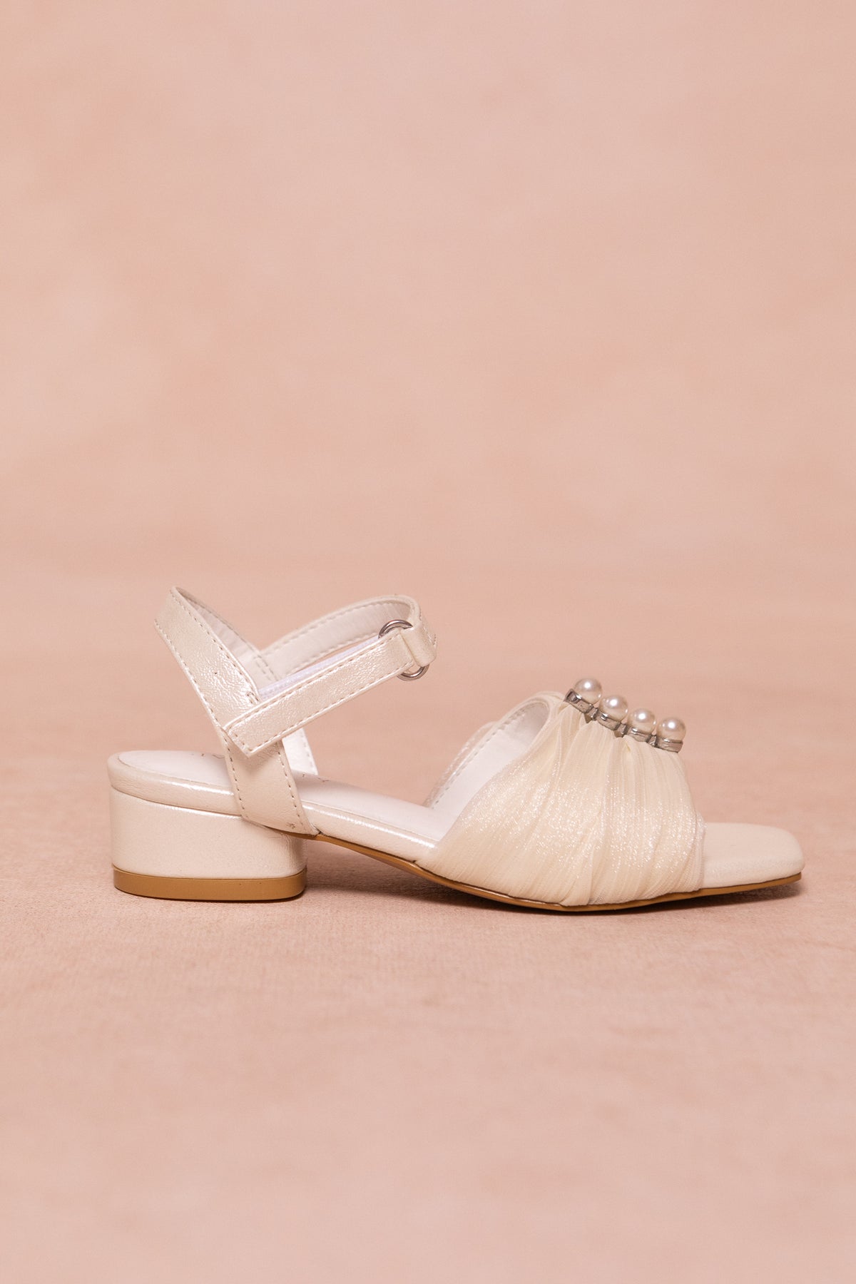 The Mini Piper Pearl Heel in Ivory by Ivy City Co is a vegan leather sandal with a low block heel, Velcro ankle strap, and gathered toe adorned with pearl-like beads—ideal girls dress shoes for special occasions.