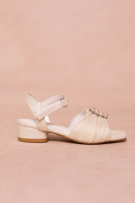 The Mini Piper Pearl Heel in Ivory by Ivy City Co is a vegan leather sandal with a low block heel, Velcro ankle strap, and gathered toe adorned with pearl-like beads—ideal girls dress shoes for special occasions.