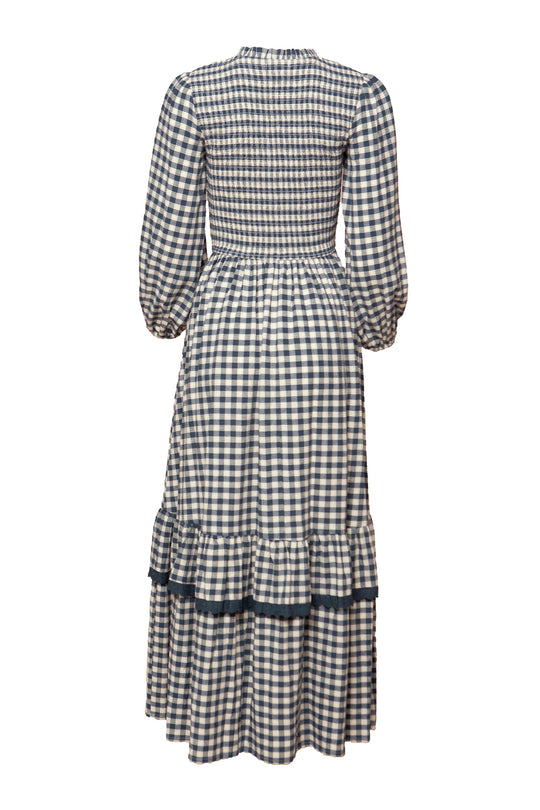 The Presley Dress in Indigo Gingham by Ivy City Co is a long-sleeved, ankle-length maxi with a smocked bodice, gathered waist, tiered ruffled skirt, and high neckline in black and white gingham, shown from the back.