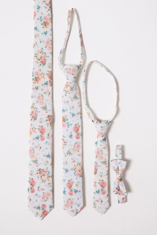 Four white ties and bow ties by Ivy City Co, adorned with the charming Countryside Peony Blossom design, are arranged vertically against a white background. These coordinated accessories are available in styles for adults, children, and infants—perfect for creating a matching family look.