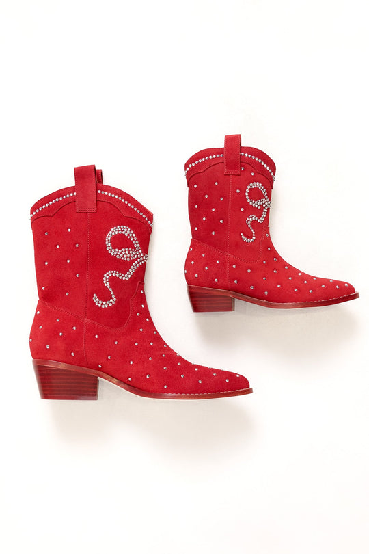 The Mini Channing Bootie in Red by Ivy City Co features vibrant red coloring, short wooden heels, small white stud accents, and a jeweled rope design on the side. Displayed against a plain white background, these booties are perfect for adding a bold pop of color to any outfit.