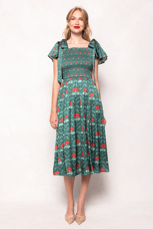 Woman wearing a green dress with red floral pattern on a white background