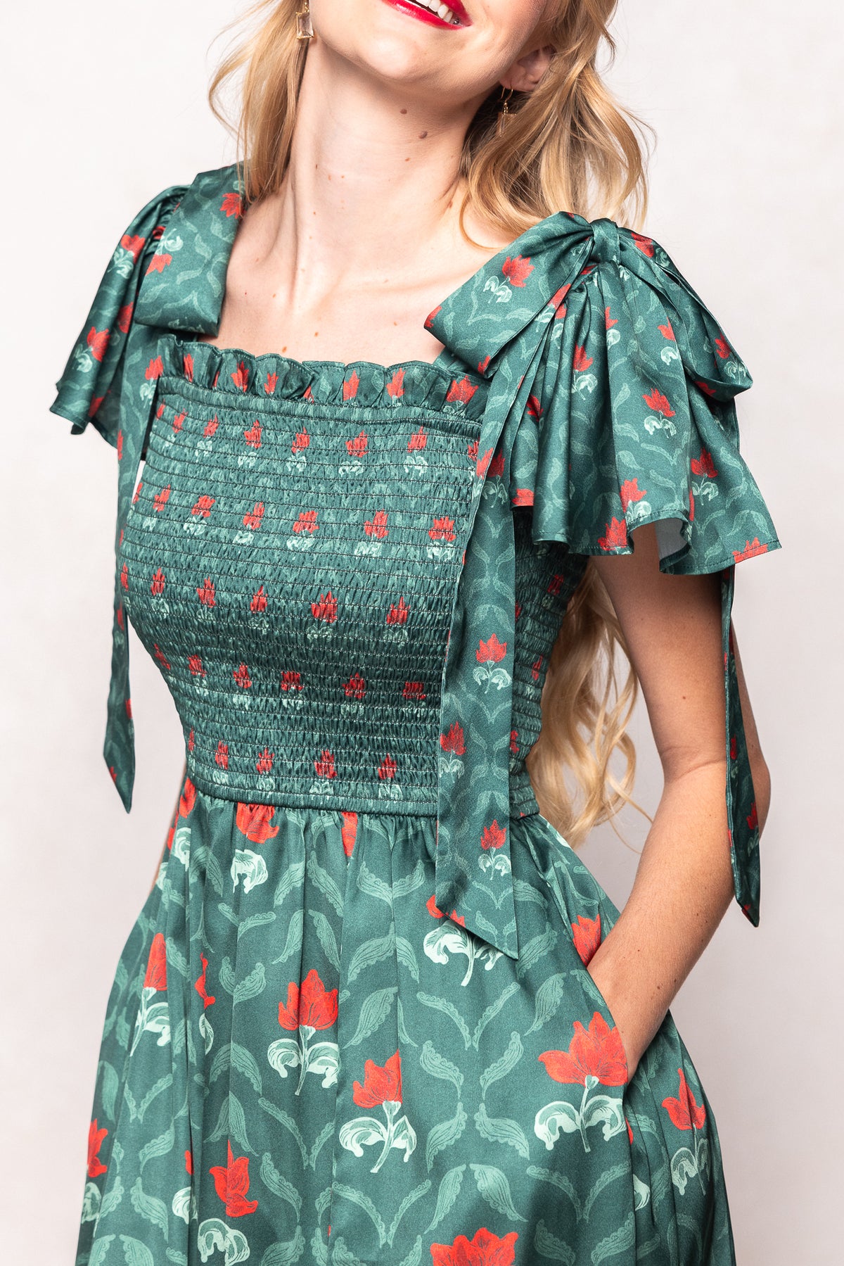 Green floral dress with bow straps worn by a person on a plain background