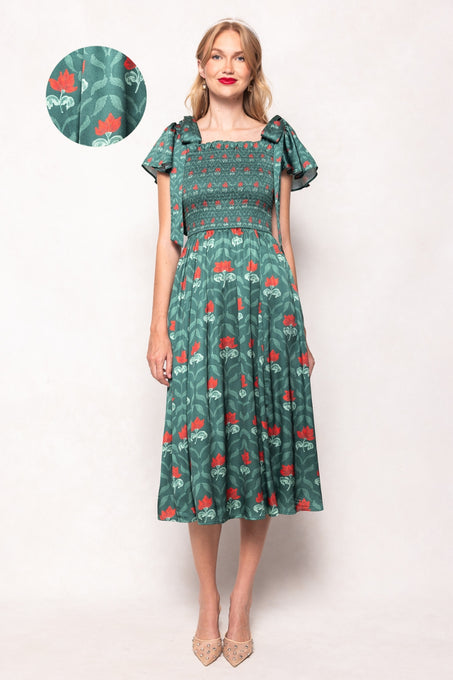 Woman wearing a green dress with red floral pattern on a white background