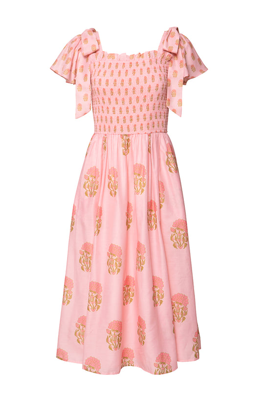 The Ivy City Co Rayna Dress in Pink Block Print features a smocked bodice, wide bow-tied straps, and a flared skirt with peach and gold florals—maternity friendly and perfect for any occasion.