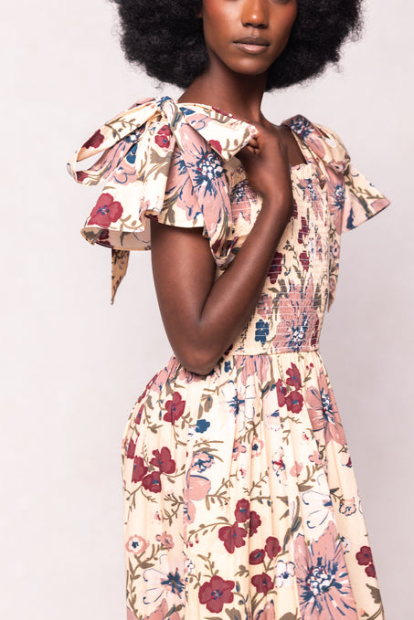 Woman wearing a floral dress with ruffled sleeves on a plain background
