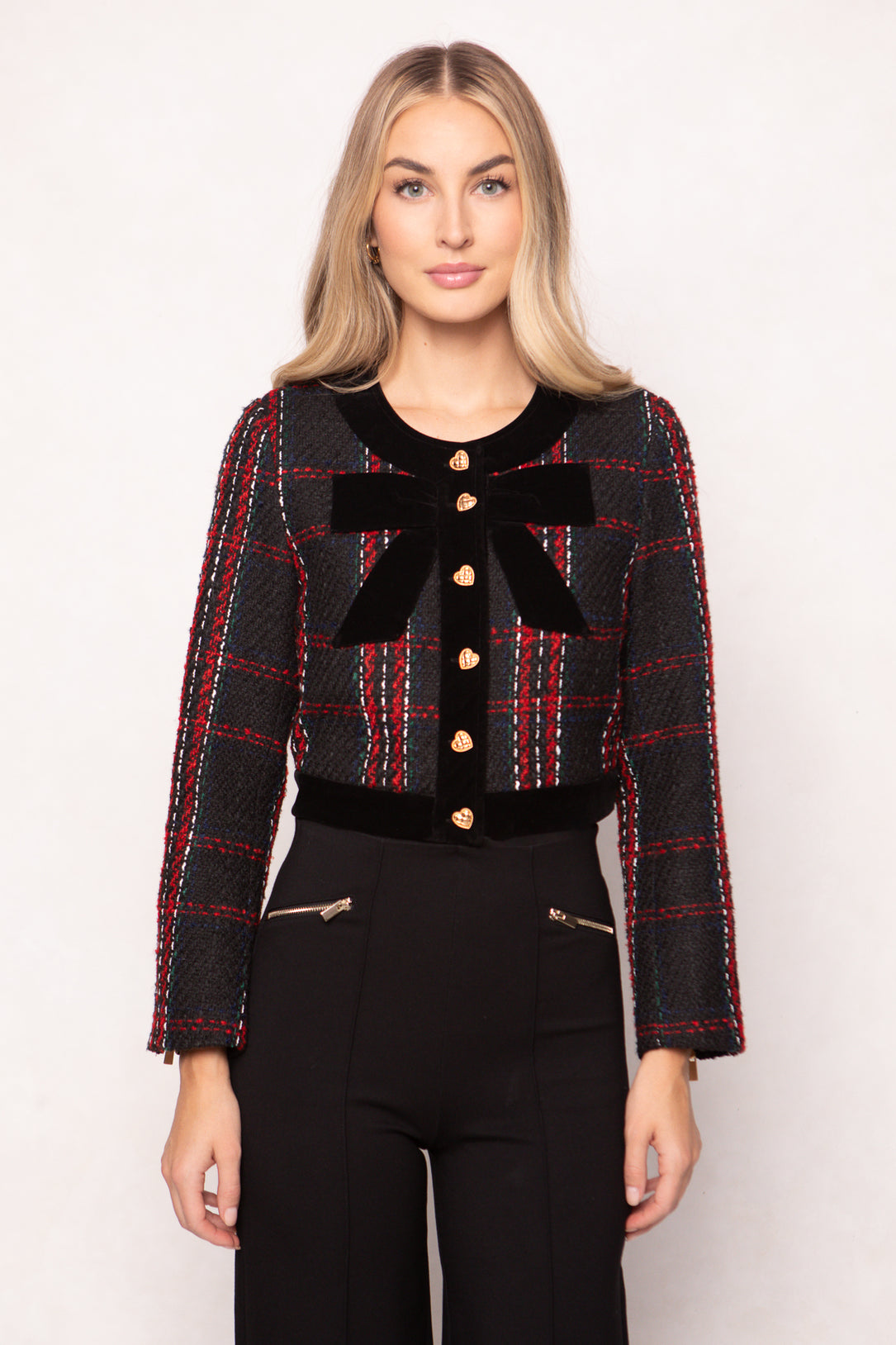 Woman wearing a black and red plaid jacket with a large bow on a white background