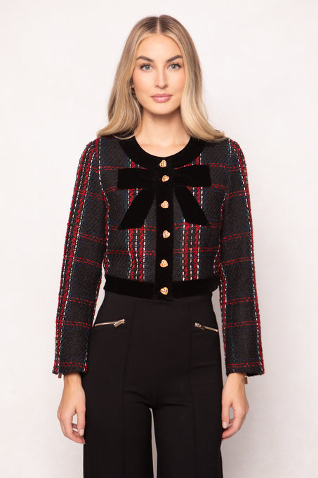 Woman wearing a black and red plaid jacket with a large bow on a white background