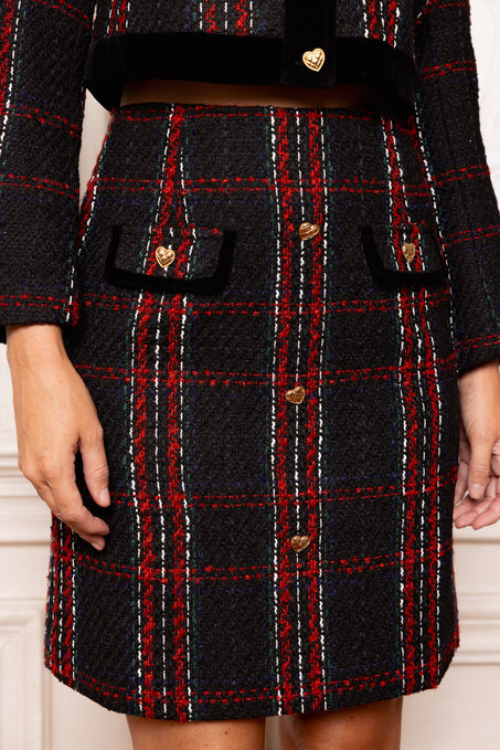 Black and red plaid coat with gold buttons on a neutral background