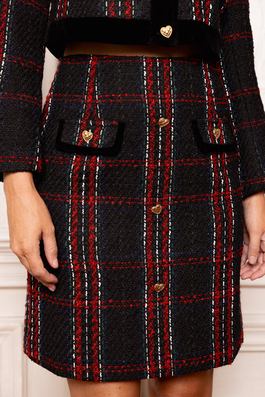 Black and red plaid coat with gold buttons on a neutral background