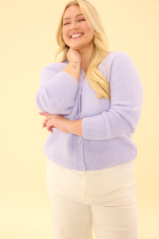 Woman wearing a light purple cardigan against a yellow background