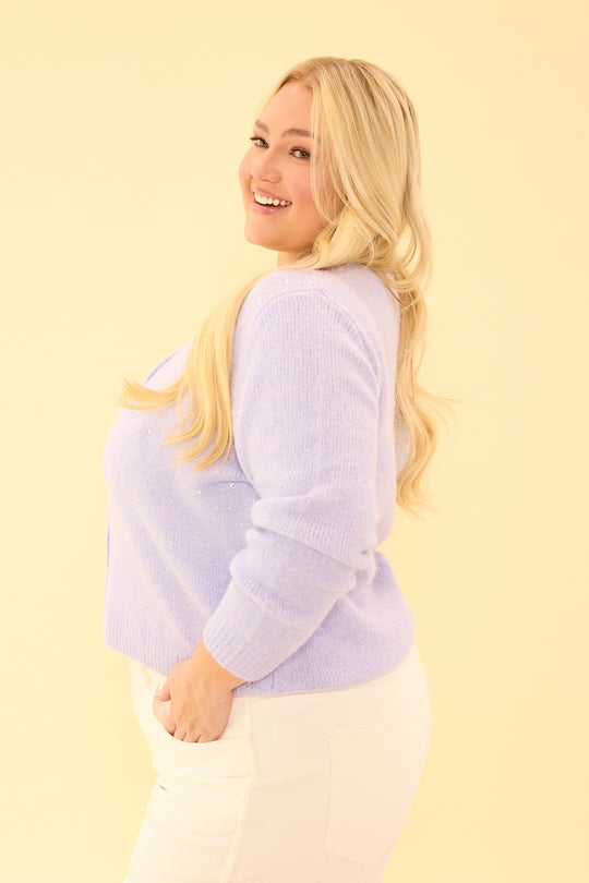 Woman wearing a light purple sweater against a yellow background