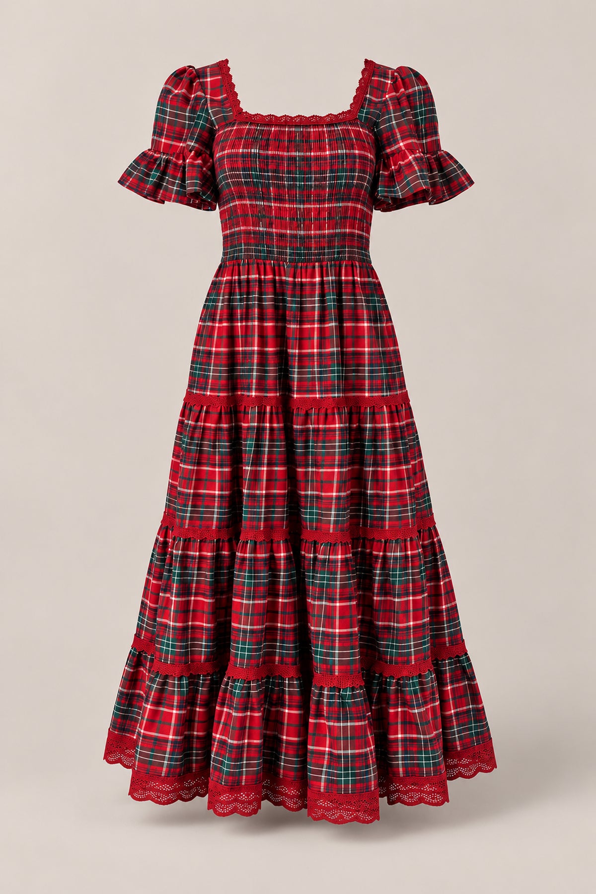 The Rosario Dress in Christmas Cheer Plaid by Ivy City Co features red plaid fabric, short sleeves, ruffled hems, a smocked bodice, and a long tiered silhouette. Displayed on a neutral background, it’s the perfect maternity-friendly choice or family photo outfit.