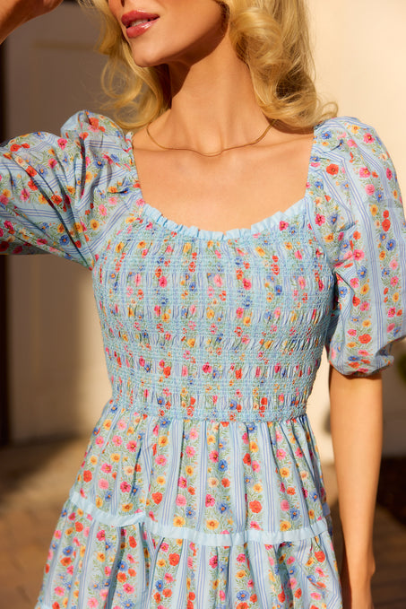 close up of a woman in a blue floral dress standing outside