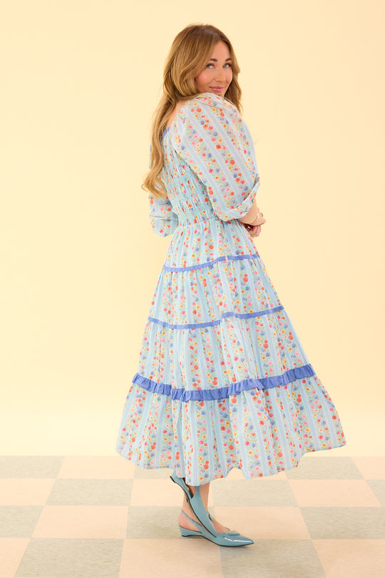 Woman wearing a floral dress on a checkered floor with a beige wall background