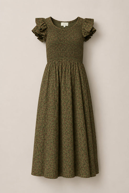 The Hattie Dress in Woodland Floral by Ivy City Co is an olive green midi dress adorned with a subtle floral pattern. It features a smocked bodice, flutter sleeves, and a gathered skirt, making it maternity friendly and allowing it to drape beautifully against a plain, light background.