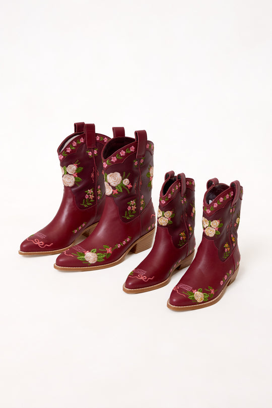 Pair of maroon cowboy boots with floral embroidery on a white background