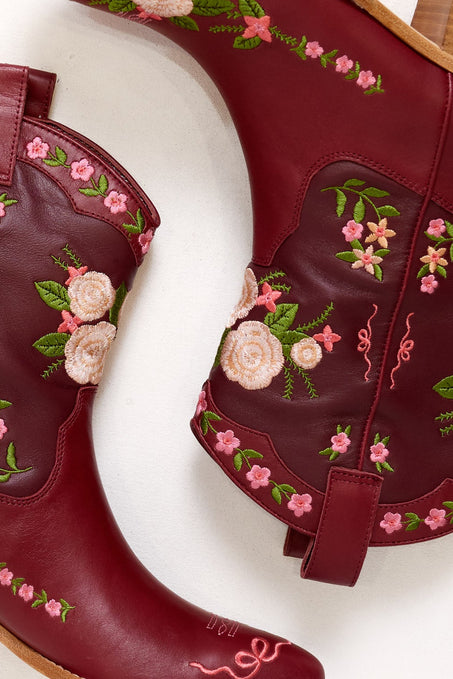 Maroon boots with floral embroidery on a white background