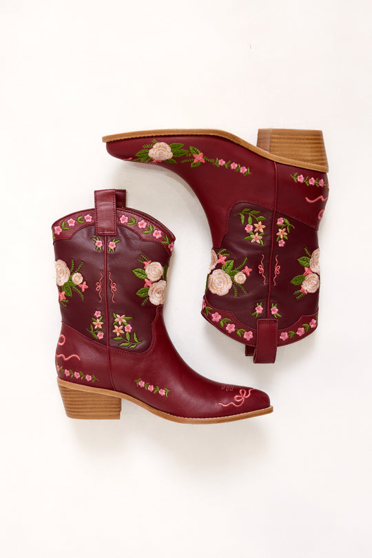 Pair of maroon cowboy boots with floral embroidery on a white background