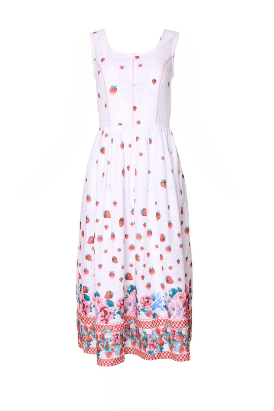 The Sadie Dress in Strawberry Vintage Tier by Ivy City Co is a sleeveless white cotton summer dress with a square neckline, red strawberry print, floral and checkered hem, fitted bodice, and gathered skirt for a timeless vintage look.