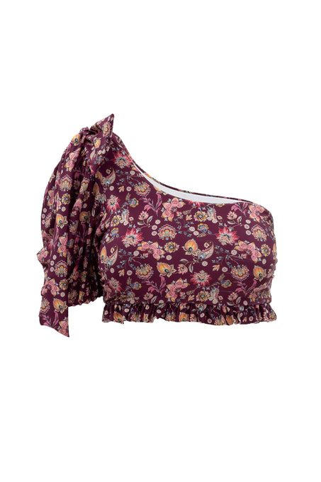 The Ivy City Co Sailor Top in Stephanie Floral is a one-shoulder crop with a large bow on the left strap and ruffled hem, featuring a maroon base with pink, yellow, and green floral pattern.