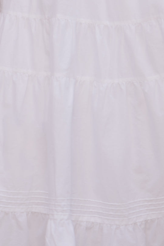 A close-up of the Sansa Skirt in White by Ivy City Co, featuring tiered, gathered cotton voile with horizontal seams and ruffles—an airy, ankle-length maternity-friendly design showcasing delicate texture.